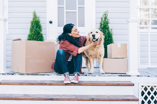 Woman and golden retriever cuddling on doorstep of new home