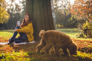 Woman sitting patiently waiting while her dog is sniffing
