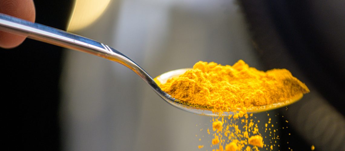 turmeric powder falling from a spoon.